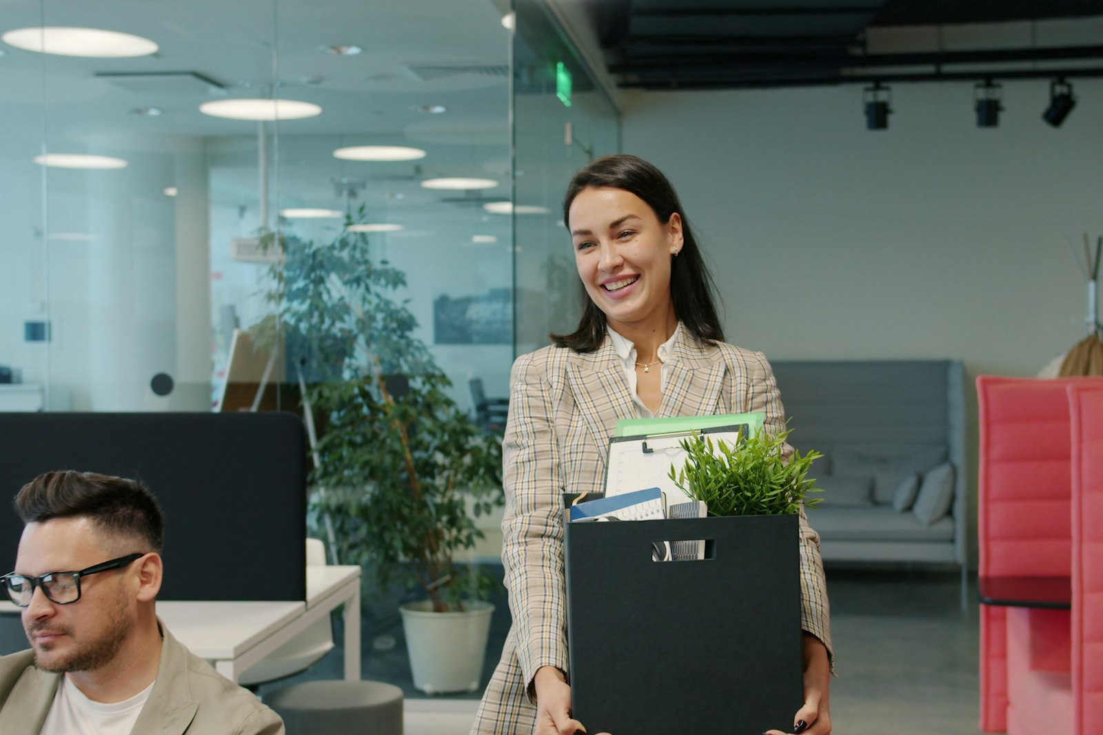 A woman carrying a box of belongings out of an office