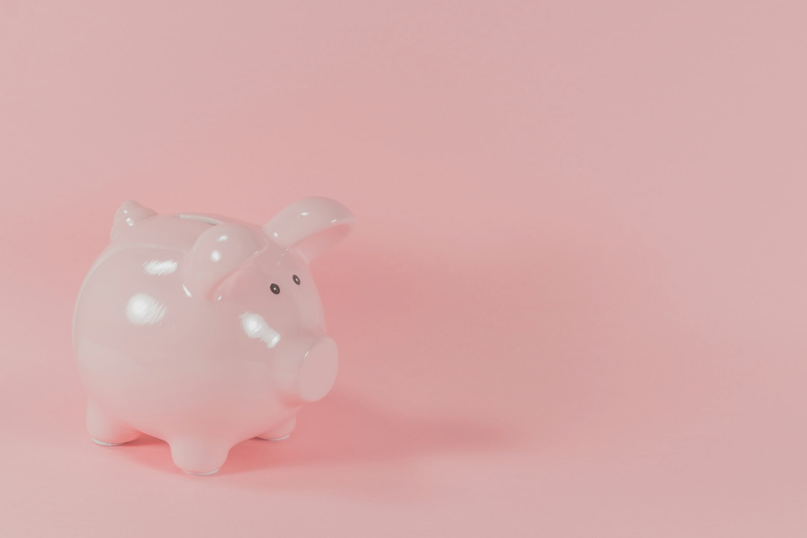 A pink ceramic piggy bank on a pink background