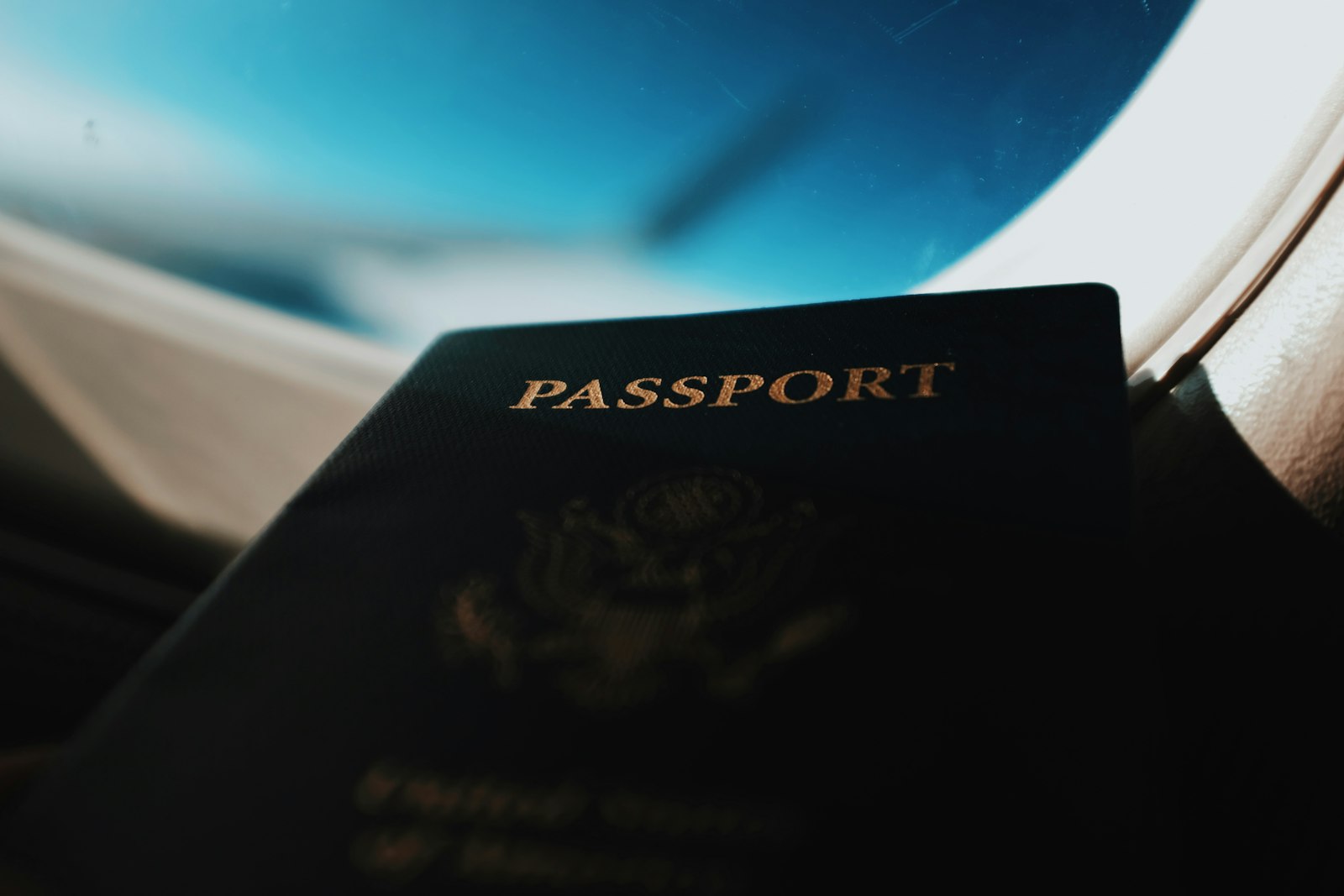 A U.S. passport held up near an airplane window